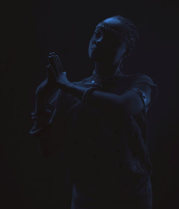 Woman performing a gentle yoga pose in a calm, dark environment with light blue accents.